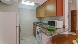 Eine kompakte Küche mit Waschmaschine, Mikrowelle und Arbeitsplatte aus Granit.
