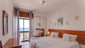 Ein Hotelzimmer mit einem großen Bett, einem Schreibtisch, einem Spiegel und Blick aufs Meer.