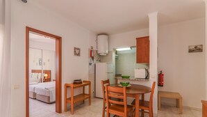 Eine kleine Küche mit Esstisch, Stühlen, Kühlschrank, Mikrowelle und einer kleinen Bank.