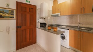 Een kleine keuken met een magnetron, oven, spoelbak en wasmachine.