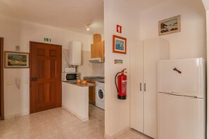 A kitchen with a microwave, washing machine, and a fire extinguisher mounted on the wall.