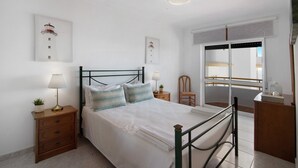 A bedroom with a bed, bedside tables, lamps, a chair, and artwork on the walls.