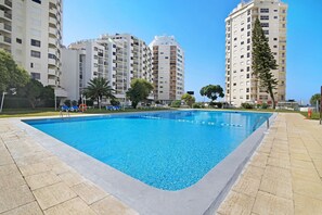 Una piscina circondata da grattacieli, cielo sereno e qualche area verde.
