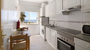 A kitchen with a view, a washing machine, a stove, and a dining area with a table and chairs.