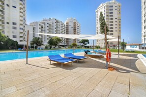 Un espace aménagé au bord de la piscine, avec des chaises longues, une bouée de sauvetage et un panneau indiquant « H2O ».