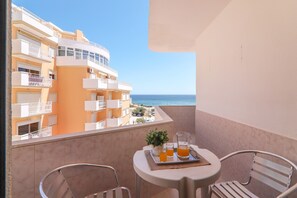 A balcony with a table, two chairs, a tray with drinks, and a potted plant. - Apt. Torre Sol 4th7 – Beachfront, A/C, Pool (Armação de Pêra)