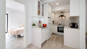 A compact kitchen with white cabinetry, a built-in oven, and a microwave. - Apt. Torre Sol 10th 6 - Sea View, A/C and Pool (Armação de Pêra)