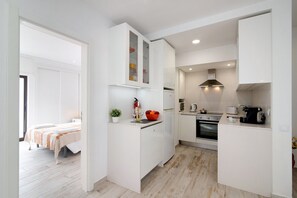 A compact kitchen with white cabinetry, a built-in oven, and a microwave.