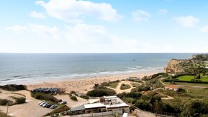 A coastal view with a beach, a parking area, and a building with a flat roof. - Apt. Torre Sol 10th 6 - Sea View, A/C and Pool (Armação de Pêra)