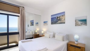 Une chambre d’hôtel avec un grand lit, une table de chevet avec une lampe, un miroir et des œuvres d’art accrochées au mur.