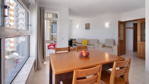 Ein modernes Wohnzimmer mit einem Holzesstisch, einer Couch und einem großen Fenster mit Vorhängen.