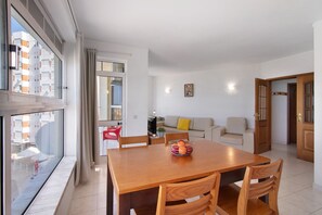 Un salon moderne avec une table à manger en bois, un canapé et une grande fenêtre agrémentée de rideaux.