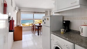 Eine Küche mit Waschmaschine, Kaffeemaschine und Blick auf den Ozean.