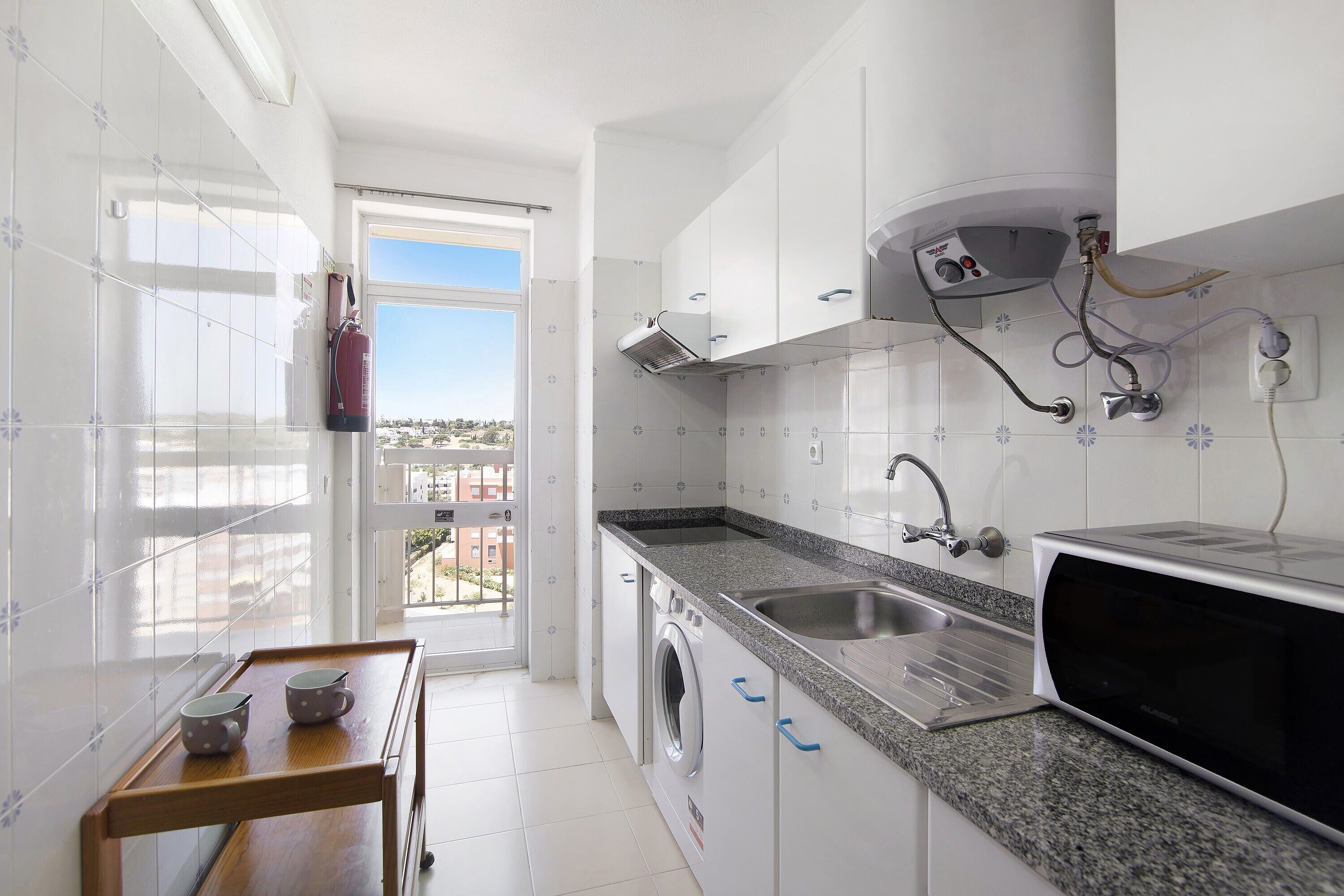 Une cuisine moderne équipée d’un lave-linge, d’un four à micro-ondes et d’un évier.