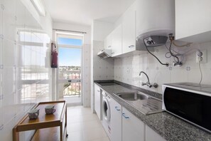 A modern kitchen with a washing machine, a microwave, and a sink.