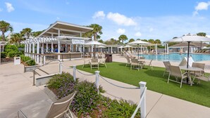 Un área junto a la piscina con sillones de descanso, sombrillas y un bar llamado 'Cappuccino Lounge'.