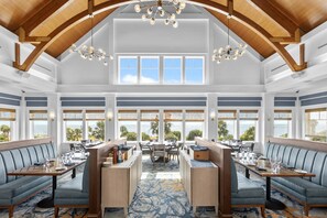 A spacious dining area with high ceilings, large windows, and a central island.
