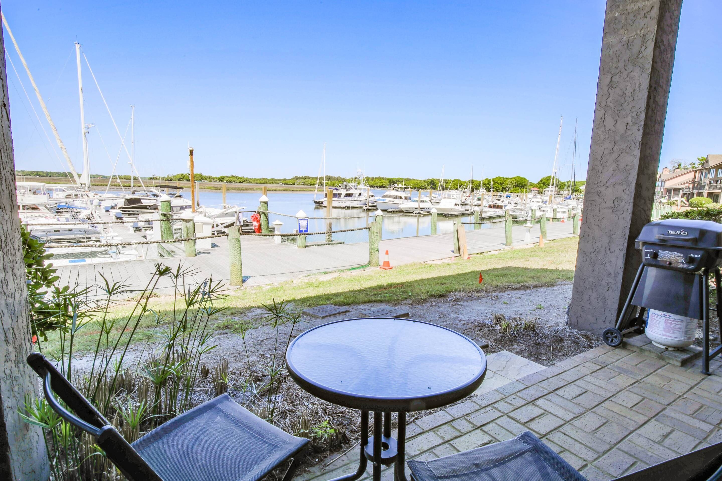 Un patio con mesa y sillas que da a un puerto deportivo con barcos.
