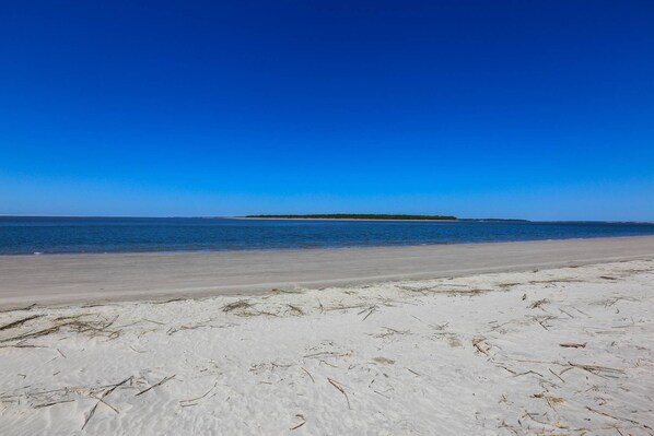 A beach with white sand and a clear blue sky.