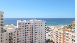 A high-rise building with multiple balconies overlooking a coastal area with a beach and ocean. - Oura 11th Floor Beach Apartment with Sea View, Pool, A/C, Wi-Fi, Garden & Balcony (Armação de Pêra)