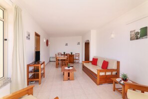 Un salon comprenant un canapé, un téléviseur, une table à manger et des chaises.