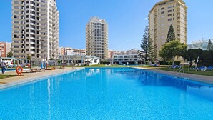 Una piscina con sillones de descanso y un flotador salvavidas, rodeada de edificios residenciales altos.