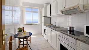 Una cocina con ventana, lavadora, estufa y microondas.