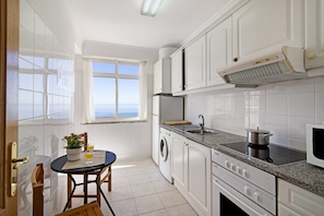 A kitchen with a window, washing machine, stove, and microwave.
