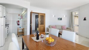 Una cocina moderna con lavadora, una mesa de comedor con una botella de vino y un bol de limones.