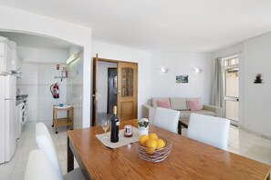 Una cocina moderna con lavadora, una mesa de comedor con una botella de vino y un bol de limones.