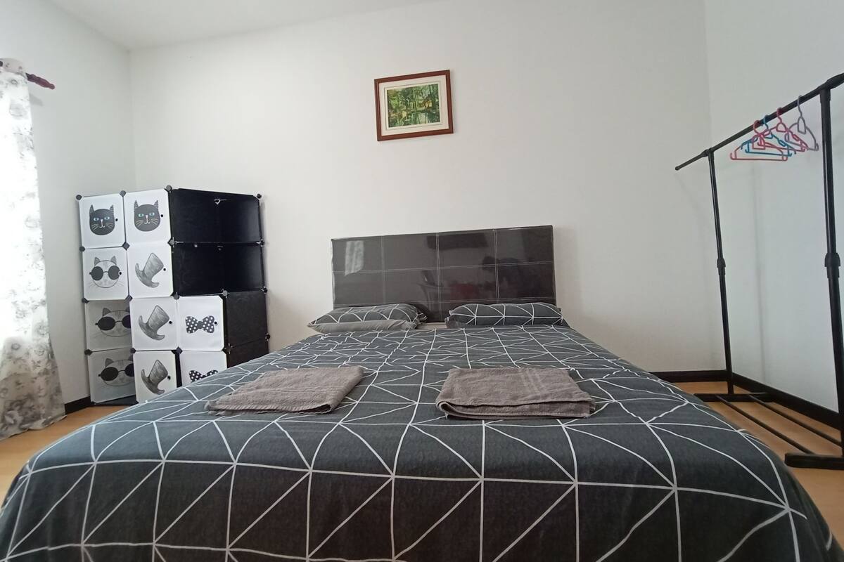Een netjes ingerichte slaapkamer met een groot bed, een kledingkast en een ingelijst schilderij aan de muur.