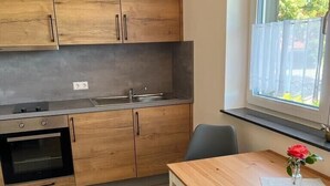Eine moderne Küche mit Holzschränken, einem eingebauten Backofen und einem Fenster mit Blick auf Grünflächen.