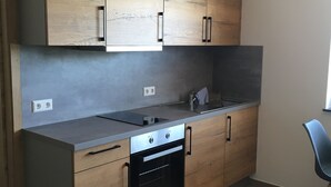 Eine moderne Küche mit Holzausstattung, einem eingebauten Backofen und einer Edelstahl-Arbeitsplatte.