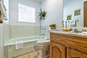A bathroom with a bathtub, toilet, vanity with a mirror, and a window. - 05210 - 8 South Pego Way (Hot Springs)