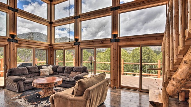 A spacious living area with a large sectional sofa, a round coffee table, and a wooden log accent. - Spacious, Luxe Cabin w/ Mtn Views, Sauna & More! (Villa Grove)
