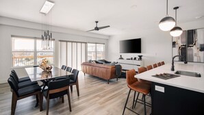 A modern kitchen with a large island, a dining area with a long table, and a living area with a sofa and chairs. - Gorgeous Reunion Lodge with 2 Decks + Patio, Resrot Amenities, Ticket & Golf Deals! (Branson)