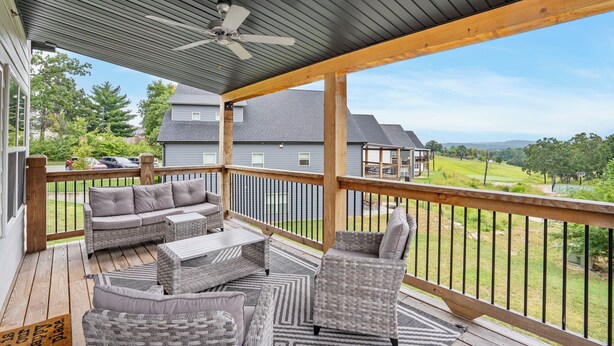 A covered outdoor deck with wicker furniture, a ceiling fan, and a view of a golf course. - Gorgeous Reunion Lodge with 2 Decks + Patio, Resrot Amenities, Ticket & Golf Deals! (Branson)
