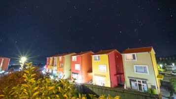Un hilera de edificios de apartamentos coloridos por la noche, con ventanas y balcones visibles.