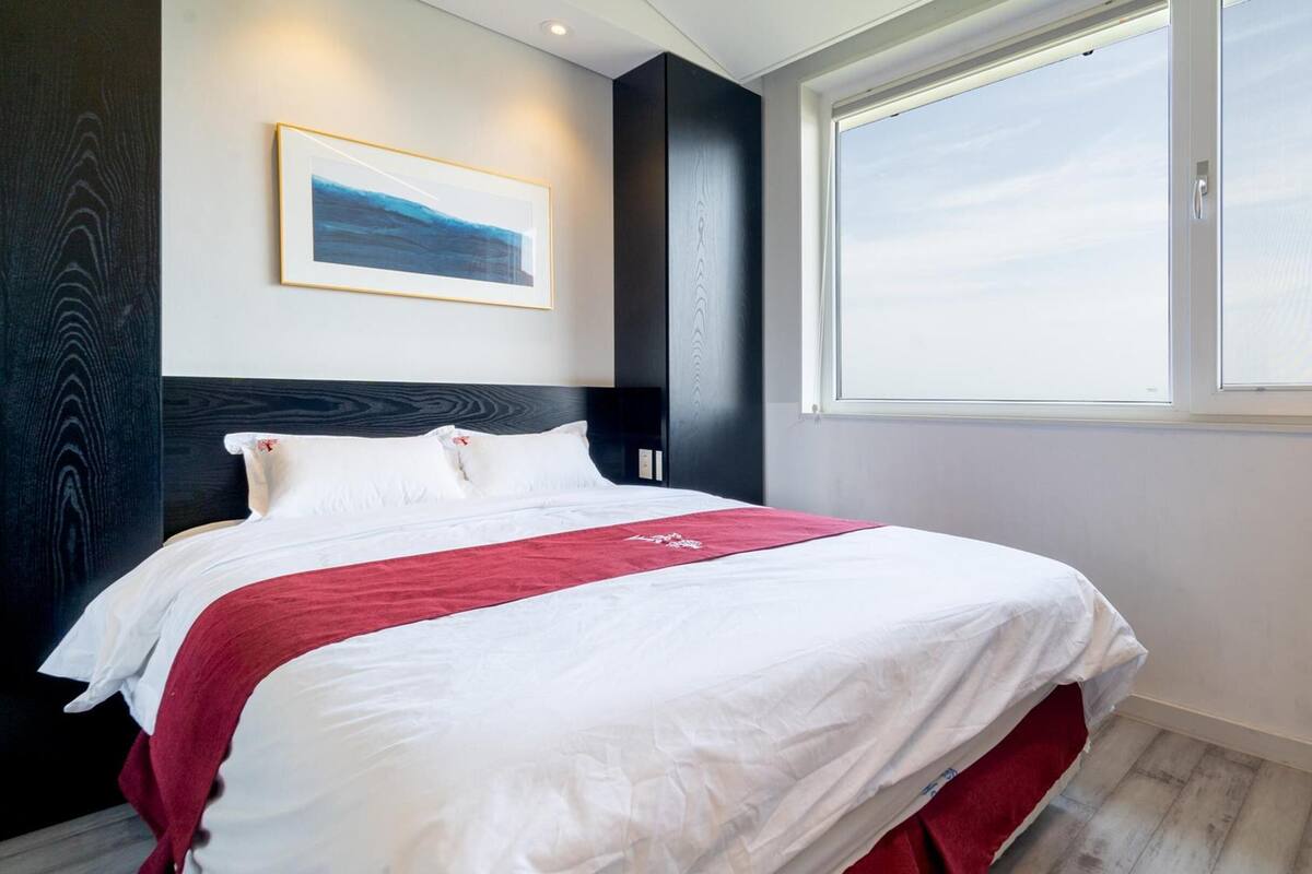 Una habitació d'hotel moderna amb un llit gran, un quadre a la paret i una finestra amb vistes.