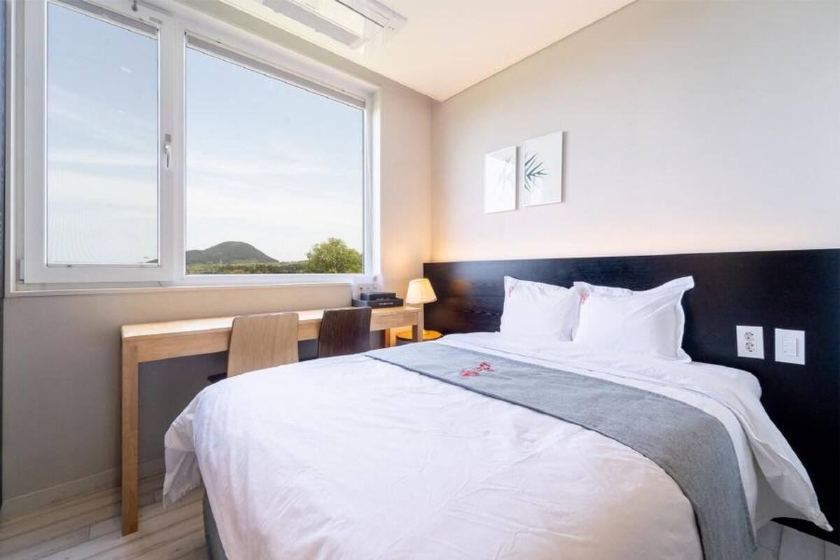 Habitació d'hotel amb llit, escriptori i finestra que dona al paisatge.