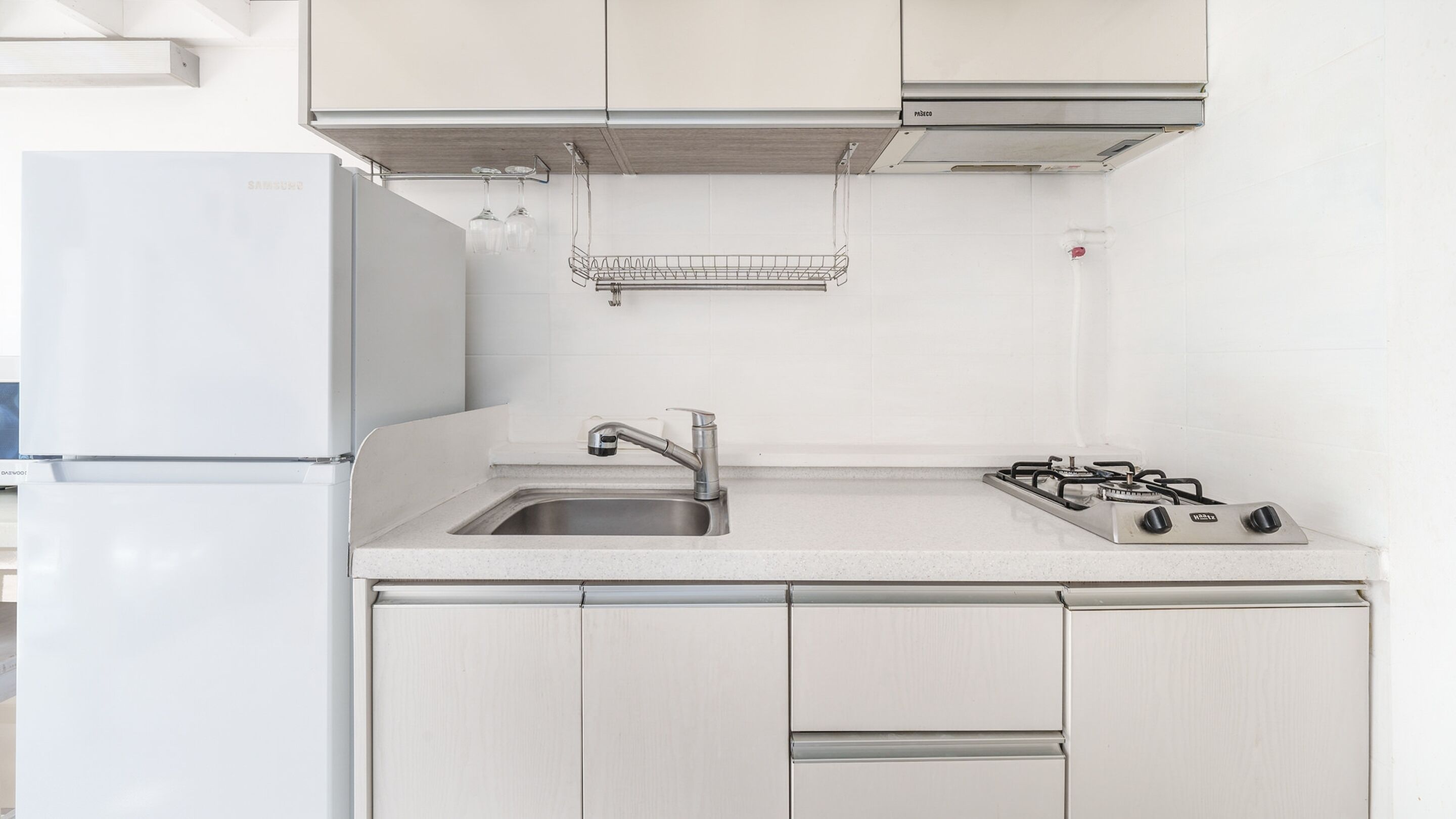 A kitchen with a white refrigerator, stainless steel sink, and gas stove.