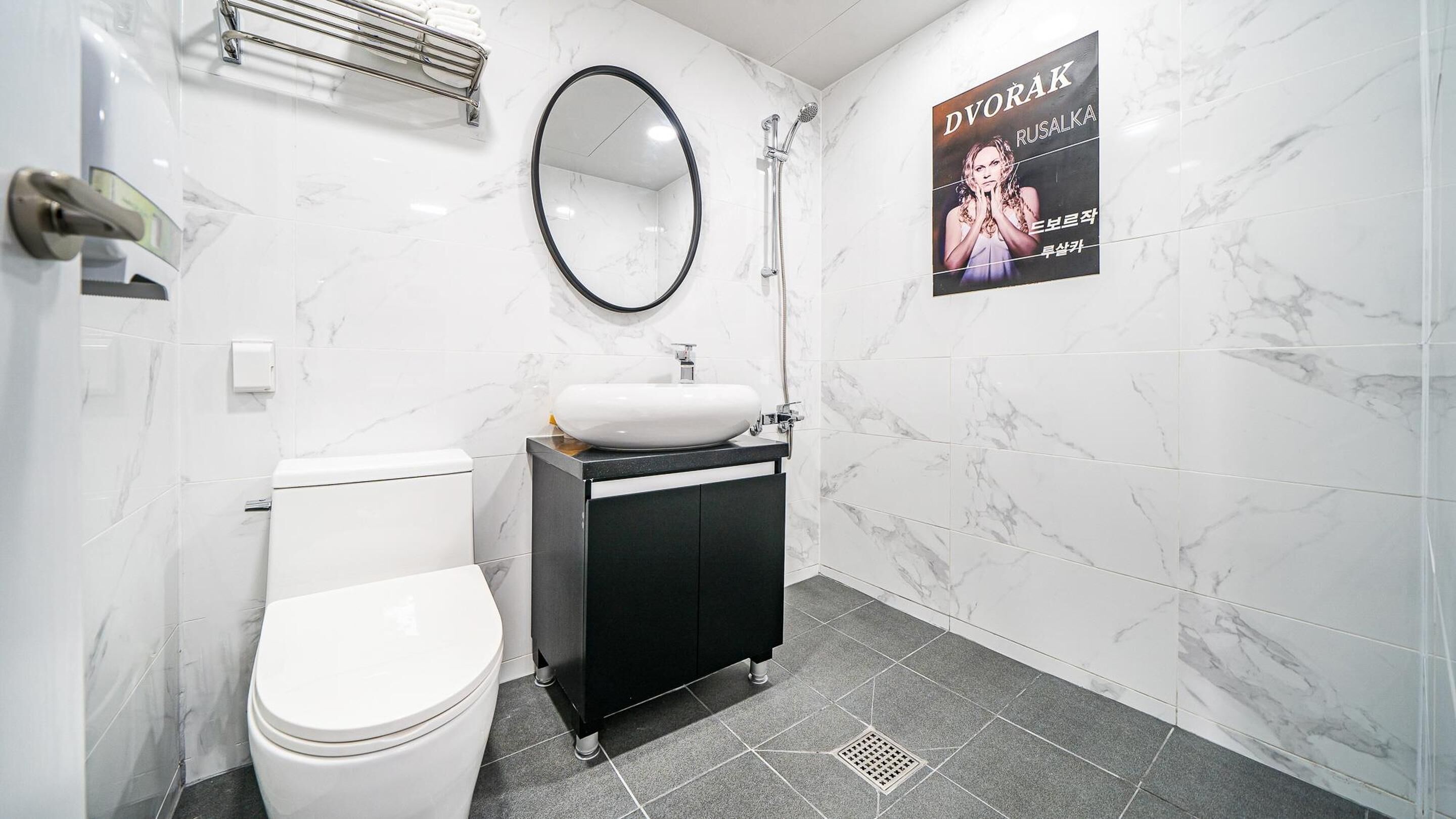 A bathroom with a toilet, a sink, a mirror, and a shower.