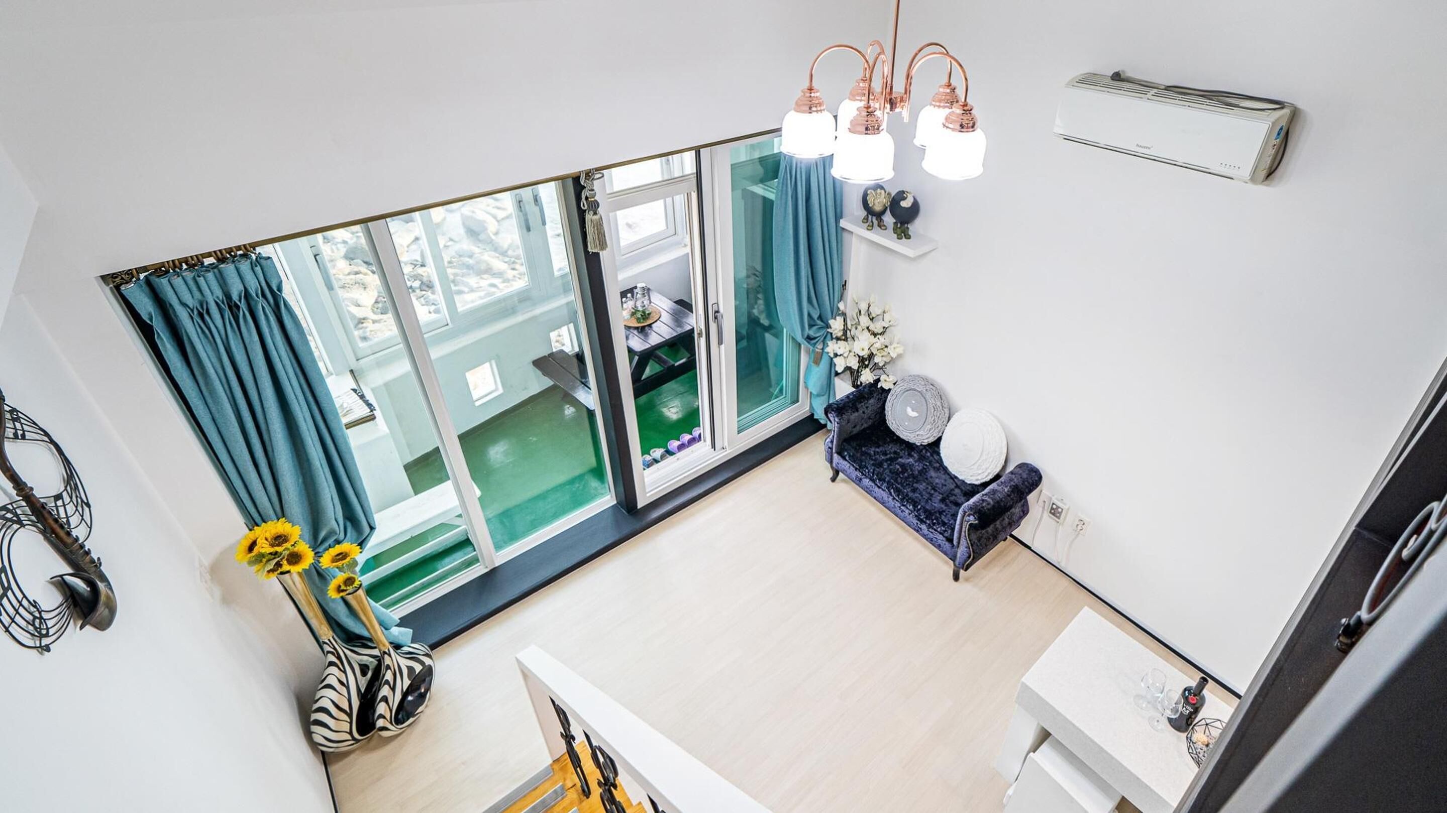 Una sala de estar moderna con un amplio ventanal corredera, un sofá azul y una pequeña mesa con adornos.