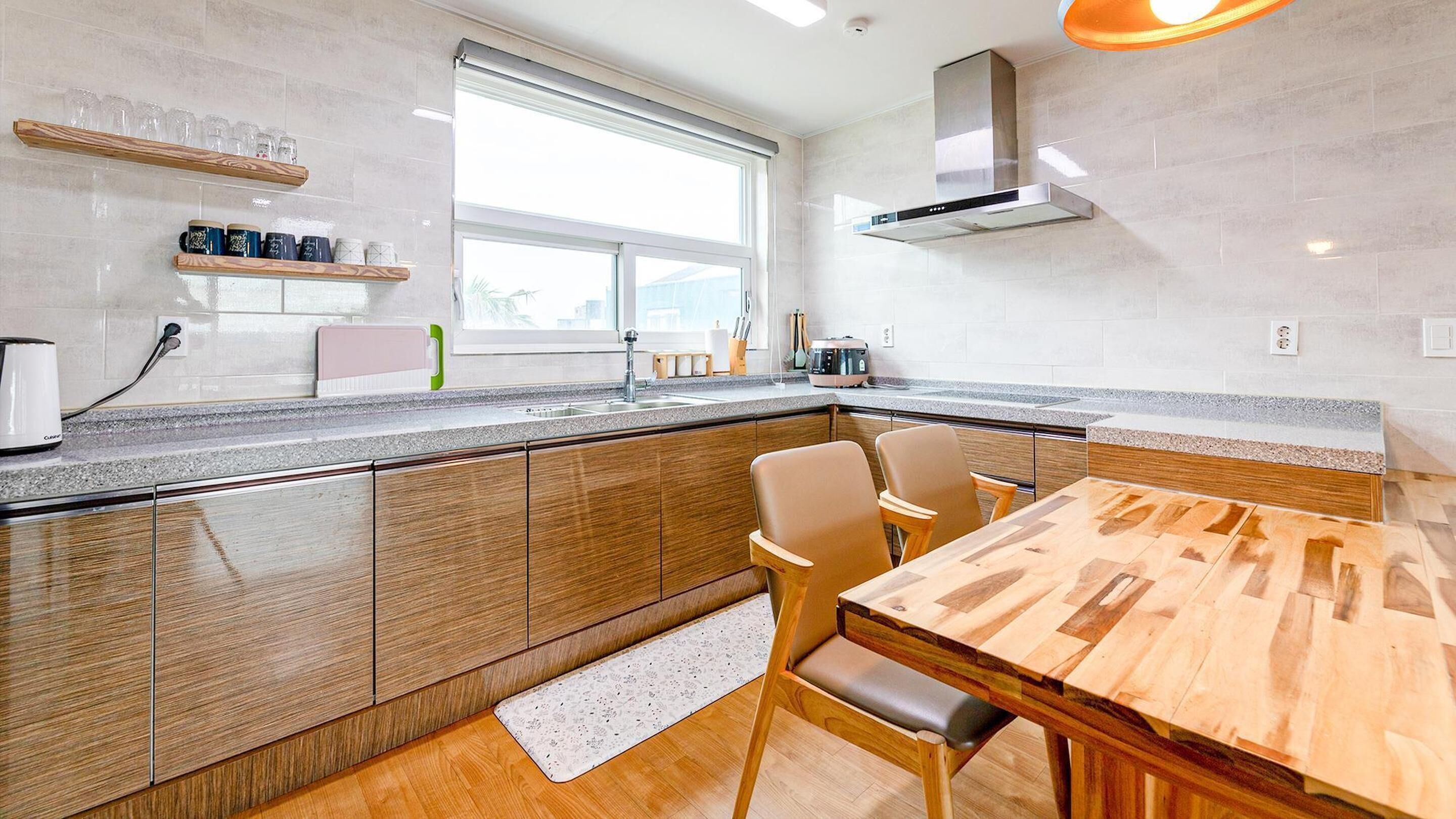 Una cocina moderna con una mesa y sillas de madera, una ventana y una estufa empotrada.