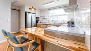 A modern kitchen with a wooden island, stainless steel appliances, and a large window.
