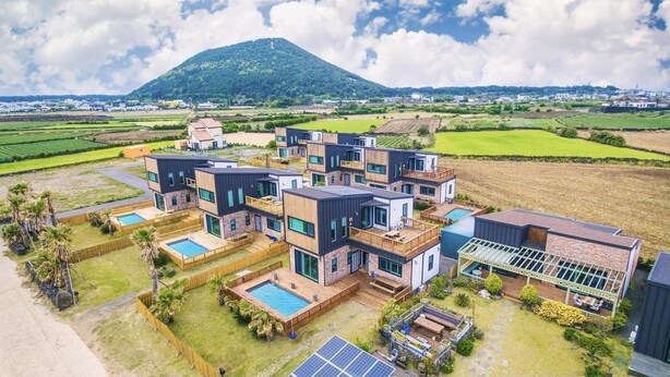 A modern multi-story house with a swimming pool, solar panels, and a view of a mountain.