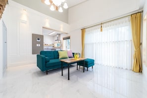 A spacious living area with a teal sofa, a wooden coffee table, and a kitchen in the background. - Pohang Ohdoheal Poolvilla (Pohang)