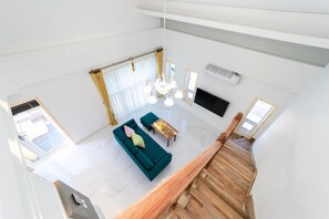 A spacious living area with a green sofa, a wooden coffee table, and a chandelier. - Pohang Ohdoheal Poolvilla (Pohang)