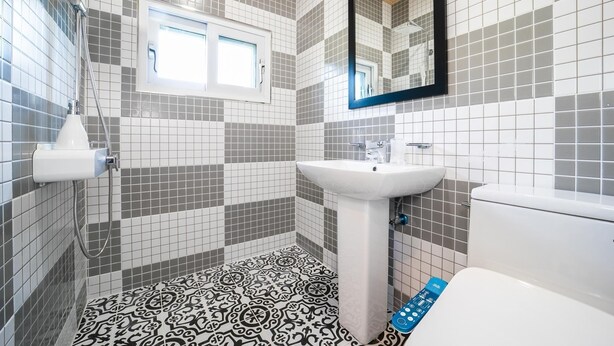 A bathroom with a tiled floor, a sink, a toilet, and a shower. - Pohang Ohdoheal Poolvilla (Pohang)
