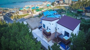 A modern two-story house with a swimming pool, surrounded by greenery and a coastal view. - Pohang Ohdoheal Poolvilla (Pohang)